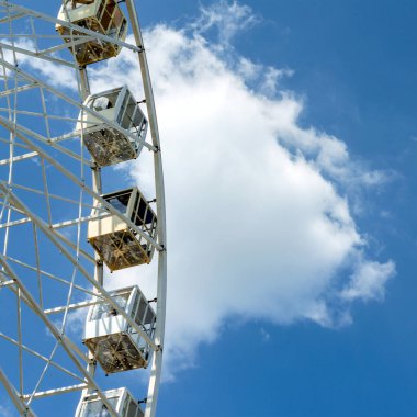 Eğlence. Büyük beyaz dönme dolabın bir parçası. Mavi gökyüzü arka planında camdan kulübeler var. Lunaparkta. Uzayı kopyala Kare.