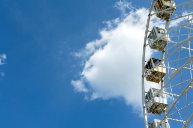 Eğlence. Büyük beyaz dönme dolabın bir parçası. Mavi gökyüzü arka planında camdan kulübeler var. Lunaparkta. Uzayı kopyala Yakın plan..