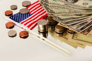 Farklı Amerikan paraları ve banknotları ve Amerikan bayrağı yansıtan yüzeyde yatıyor..