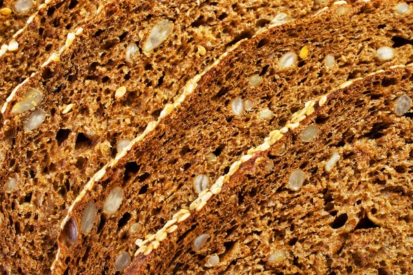Ayçiçeği tohumlu koyu çavdar ekmeği. Dilimlenmiş parçalar, seçici odaklanma. Yemek konsepti için doku ve desenler. Makro. Yatay çekim.