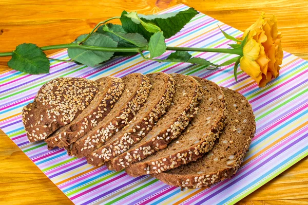 Yiyecek, taze doğranmış ekmek ve sarı ahşap bir zemin üzerindeki peçetenin üzerindeki sarı bir gül bileşimidir. Yakın plan..