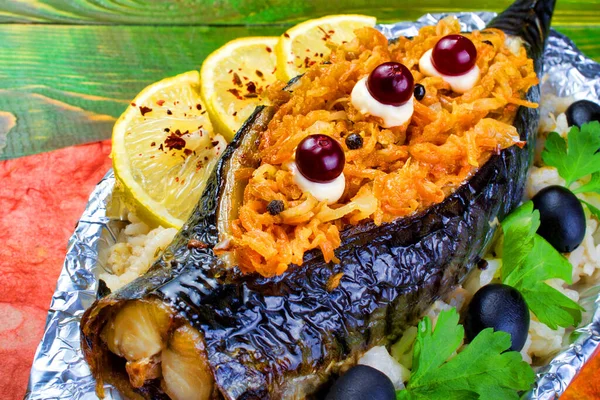 Havuçla doldurulmuş fırında uskumru balığı. İçinde haşlanmış pirinç bulunan folyoya sarılmış maydanoz. Yeşil ahşap arka planda. Yakın plan..