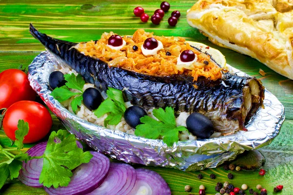 İçine havuç, zeytin, maydanoz, domates ve kırmızı soğan doldurulmuş fırınlanmış uskumru balığı folyoya sarılmış bir tabakta, içinde haşlanmış pirinç var. Yeşil ahşap arka planda. Yakın plan..