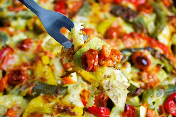 Gril renkli ekolojik yaz sebzeleri, çatalın üzerine rendelenmiş peynir serpiştirilmiş, fırında pişirilmiş. Çok renkli vejetaryen gıda geçmişi. Üst Manzara. Yakın plan..