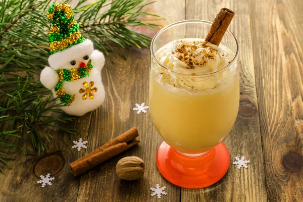 Noel içeceği: Tarçınlı yumurta likörü, hindistan cevizi ve ahşap arka planda krema. Ve oyuncak bir kardan adam. Geleneksel Noel tatlısı. Seçici odak