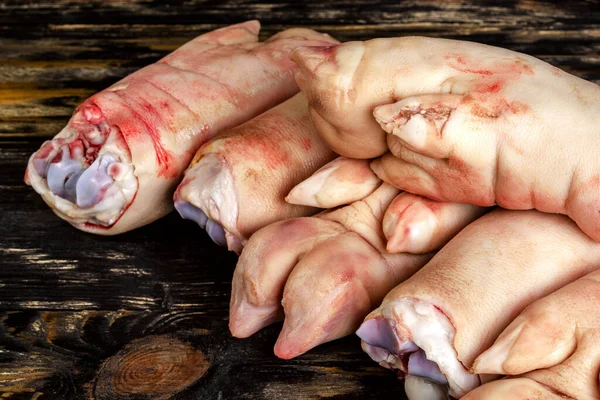Koyu ahşap tahtada çiğ domuz ayağı ya da bacakları. Yığınla var. Et aşısı. Yakın plan..