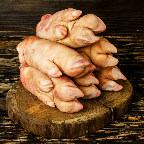 Koyu ahşap tahtada çiğ domuz ayağı ya da bacakları. Yığınla var. Et aşısı. Kare. Yakın plan..