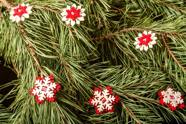 Kırmızı yapay kar taneleriyle bembeyaz süslenmiş bir Noel köknarı dalı. Yakın plan..