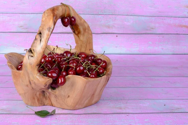 Çizgili pembe arka planda ahşap bir sepetin içindeki kiraz..