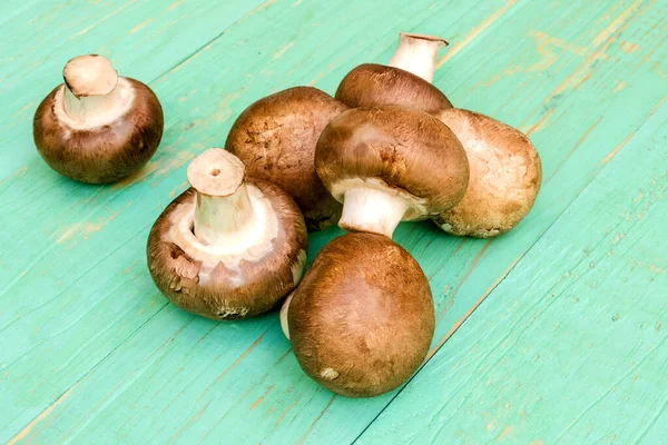 Şampiyon mantarları ve yabani çiçekli hasır sepeti. mavi ahşap bir arka planda.