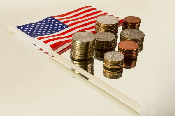 Sütundaki farklı Amerikan paraları ve yansıtıcı yüzeydeki Amerikan bayrağı.