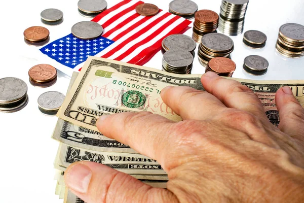Farklı Amerikan paraları, banknotları ve yansıtıcı yüzeyde Amerikan bayrağı bulunur. Ve insan eli kapladığında.
