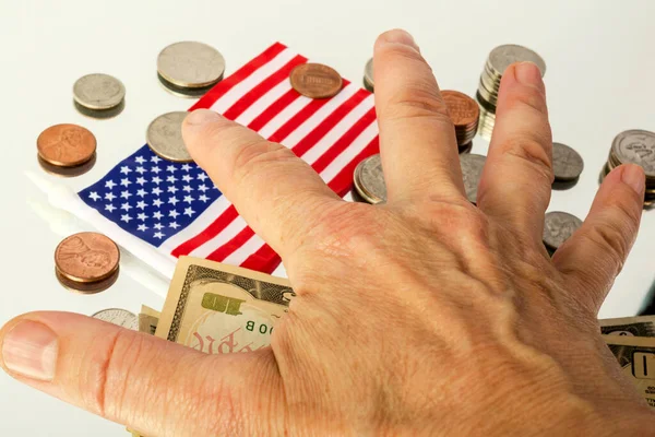 Farklı Amerikan paraları, banknotları ve yansıtıcı yüzeyde Amerikan bayrağı bulunur. Ve insan eli kapladığında.
