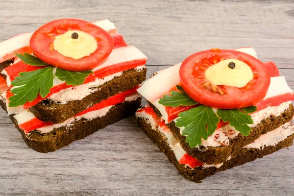 Kahvaltı menüsü olarak taze ekmek, işlenmiş peynir, yengeç çubuğu ve domates. Soyut arkaplanda.