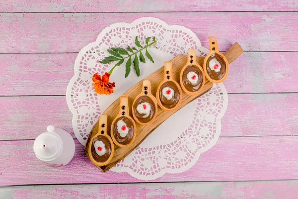 Kesme tahtasının üzerinde çikolata fındık ezmesi olan kaşık şeklinde turtalar. Ve çiçek bir kadife çiçeği. Üst görünüm.