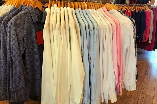 Renkli tekstil gömlekleri mağazadaki bir rafta asılı..