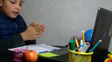 Uzaktan öğrenme, E-öğrenme. Yorgun okul çocuğu internetten eğitim alıyor ve karantina sırasında okul ödevi yapıyor. Masaüstünde okul malzemeleriyle oturuyor. Yakın plan portre.