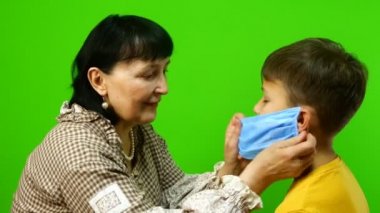 Karantina sırasında kendini izole etme. Aile içinde çocuklarla zaman geçirmek ve eğlenmek. Büyükanne ve torun koruyucu sağlık maskelerini takıp, birbirlerine sarıldılar. Krom anahtar.