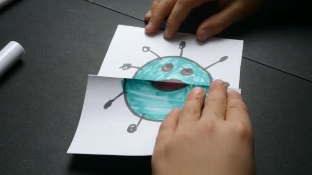 Kinderen hand speelt met handgemaakt speelgoed met afbeeldingen coronavirus op wit papier. Animatie voor kinderen tijdens quarantaine en zelfisolatie. Close-up. — Stockvideo