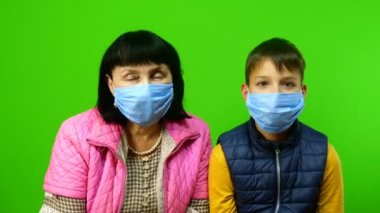 Karantina sırasında kendini izole etme. Aile içinde çocuklarla zaman geçirmek ve eğlenmek. Komik büyükanne ve torun koruyucu tıbbi maskeler takıp oynaştılar. Krom anahtar.