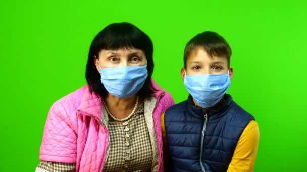 Self-isolation during quarantine. Pastime and entertainment with children in family. Funny grandmother and grandson put on protective medical masks and shake their heads. Chroma key. — Stock Video