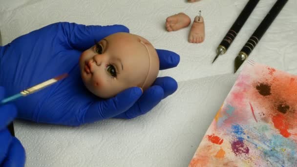 Making dolls. Master puppet intently paints lips of blank for doll with thin brush. Concept of creating handmade dolls. — Stock Video