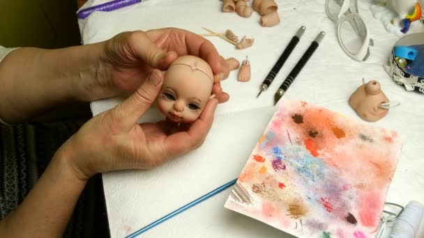 Poppen maken. Master marionet onderzoekt geproduceerd aan haar poppen hoofd. Concept van het maken van handgemaakte poppen. Close-up. — Stockvideo