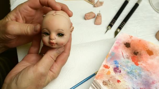 Faire des poupées. Maître marionnette examine produit à sa tête de poupée. Concept de création de poupées artisanales. Gros plan . — Video