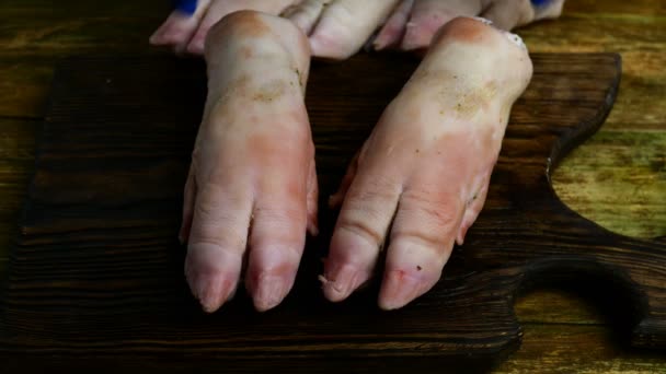 Préparation cuisses de porc. Pas à pas. Les mains humaines dans des gants en caoutchouc frappant drôle avec des sabots de porc sur la planche de cuisine en bois. Gros plan .