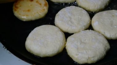 Ev yemeği. Kadın eli, kızarmış taze peynirli kek ya da kızgın yağda kızartılmış tavada şerbet. Yakın plan..