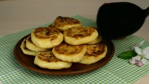 Thuis koken. Verse heerlijke cheesecakes of syrniki met gouden korst gestapeld op schotel met keukenspatel en bewaterd met jam. Close-up. — Stockvideo