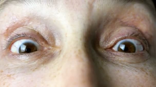 Mulher adulta madura de etnia caucasiana rapidamente pisca os olhos enquanto olha para a câmera. Close-up . — Vídeo de Stock