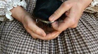 Kırsal giysili, buruşuk elleri olan yetişkin bir kadın avuç içine para atıp siyah deri cüzdanını alır ve yerine geri koyar. Yoksulluk ve finansal kriz kavramı. Kapat..