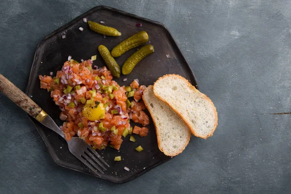 Tartare van zalm met eidooier, ingemaakte komkommer en verse uien — Stockfoto