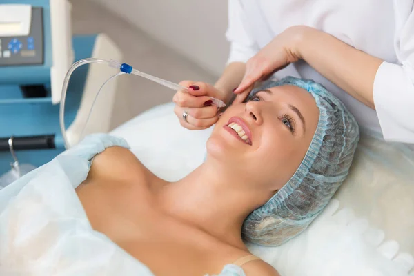 Güzel, gülümseyen bir kızın kozmetoloji kliniğinde jet peeling ameliyatı var. Sağlık hizmetleri, klinik, kozmetologlar.