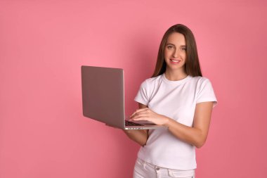 Genç iş kadını dizüstü bilgisayarda sörf yapıyor, bilgisayarda çalışıyor, gülümsüyor, keyfi yerinde, evde tek başına vakit geçiriyor.