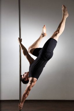 Genç, güçlü striptizci, siyah elbiseli gülümseyen adam. Tarafsız arkaplan.