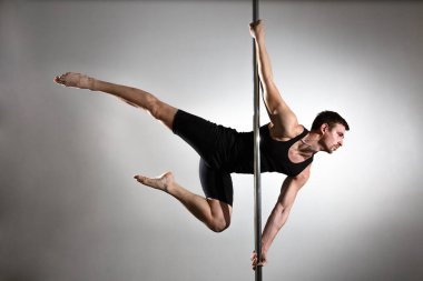 Genç, güçlü striptizci, siyah elbiseli gülümseyen adam. Tarafsız arkaplan.