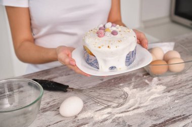 Beyaz elbiseli tanınmayan bir kadın mutfakta yemek pişirecek, elinde Paskalya Pastası olacak. Geleneksel Kulich, Paska Paskalya Ekmeği. Masanın üzerinde bir kase yumurta, bir şişe süt ve bir un var..