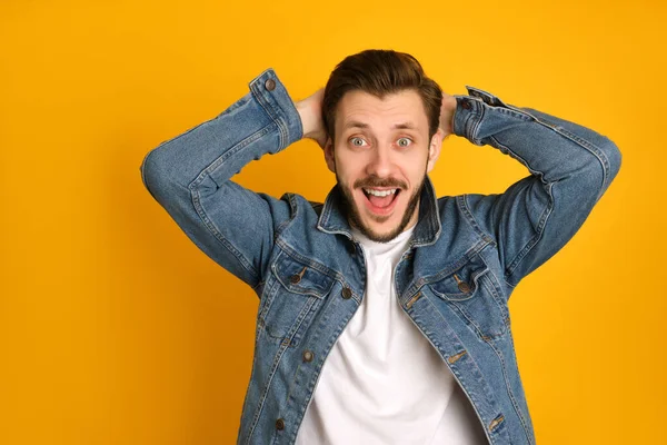 Funny young man in white t-shirt isolated on yellow background, raising his eyebrows, opening his mouth with surprise, being amazed.