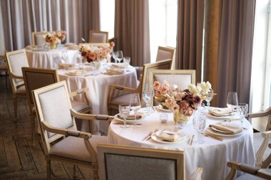 Restorandaki lüks sonbahar düğün masası dekorasyonu. Taze ve kuru çiçekler, güller, karanfiller. Güzel masa düzenleme: Altın eşyalar, çatal ve bıçak, kaligrafi misafir oturma kartı.