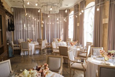 Restorandaki lüks sonbahar düğün masası dekorasyonu. Taze ve kuru çiçekler, güller, karanfiller. Güzel masa düzenleme: Altın eşyalar, çatal ve bıçak, kaligrafi misafir oturma kartı.