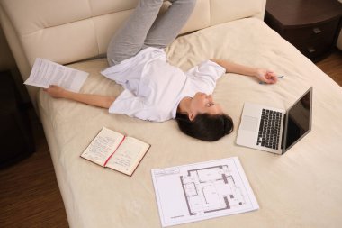 Koronovirüs salgını sırasında kendini izole eden genç kadın işadamı COVID-19 evde çalışır, yatakta uzanır, mektupları kontrol eder, uzaktan çalışmasını yapar, telesekreter olarak çalışır.