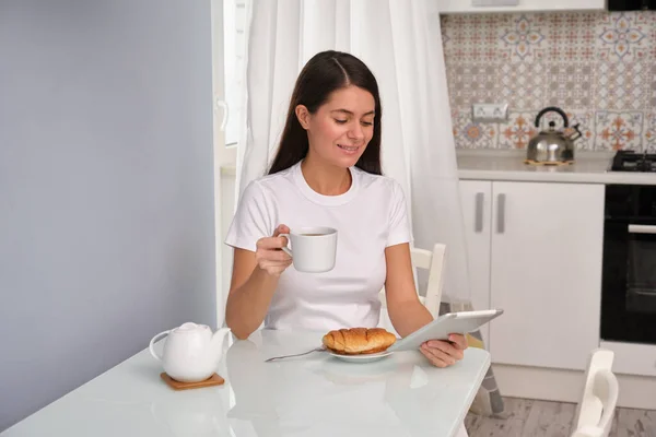 Chica Morena Está Bebiendo Con Croissant Cocina Con Una Camiseta —  Fotos de Stock