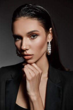 İnce ve genç bir kız, güzel ve tonlu bir vücudu var. Vücut kıyafetli ve çizmeli bir kadın. Spor, diyet, moda ve güzellik konsepti. Karanlık bir arka planda izole edilmiş. Islak saçlar. Yakın plan. Güzel küpe..