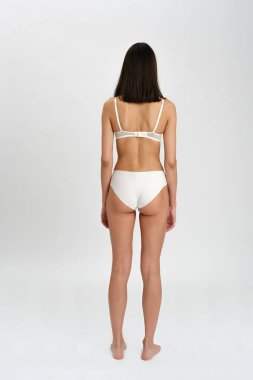 Güzel, sevimli, sevimli, sevimli, sakin, zayıf, esmer, temiz, pürüzsüz, sağlıklı bir kız. Açık gri arka planda izole edilmiş. Geri çekiliyorum. Saç kesme reklamı..