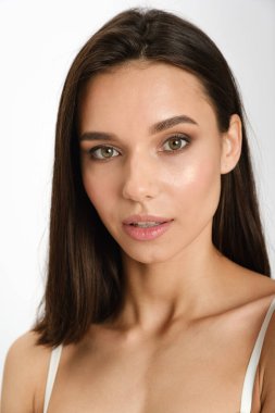 Güzel, sevimli, sevimli, sevimli, sakin, zayıf, esmer, temiz, pürüzsüz, sağlıklı bir kız. Açık gri arka planda izole edilmiş. Saç kesme ilanı. Yüzü yakın çekim.