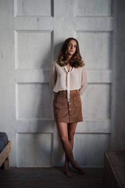 İç mekânda, güneş ışığında uzun kahverengi dalgalı genç ve şık bir kadının portresi. Oldukça sakin bir kız