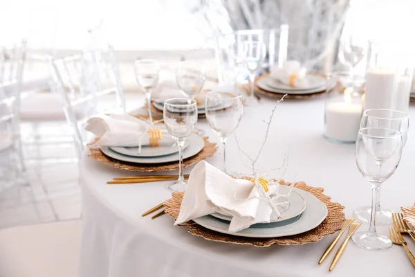 Luxurious stylish decoration of the wedding table for the winter wedding. Fresh and dried white flowers. Beautiful table setting: golden appliances, fork and knife, feather. Winter Concept