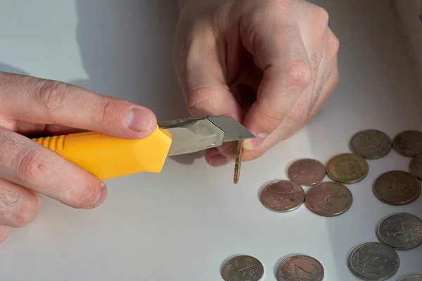 A man counts money and divides it. Round coins. Cutting of money with a knife